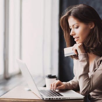 A woman with her credit card ready to make an online purchase.