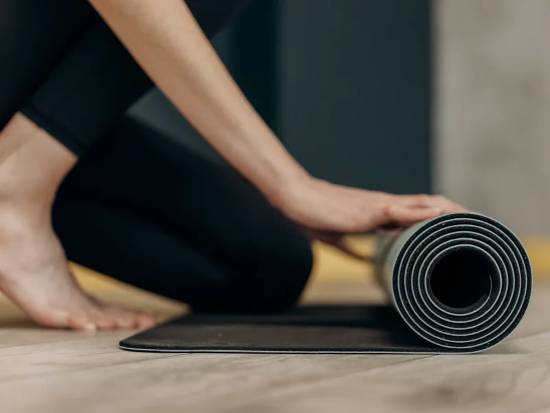 person rolling out a yoga mat