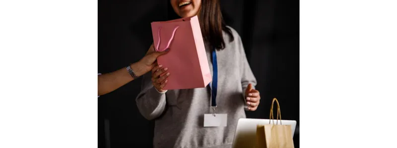 Woman receiving a pink gift bag while smiling at an event.