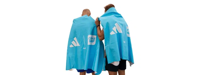 Two people wearing large blue branded towels at an event