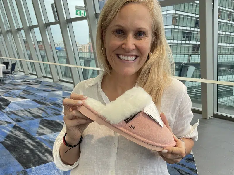 Delegate showcasing custom engraved UGG scuff slipper at international leadership event