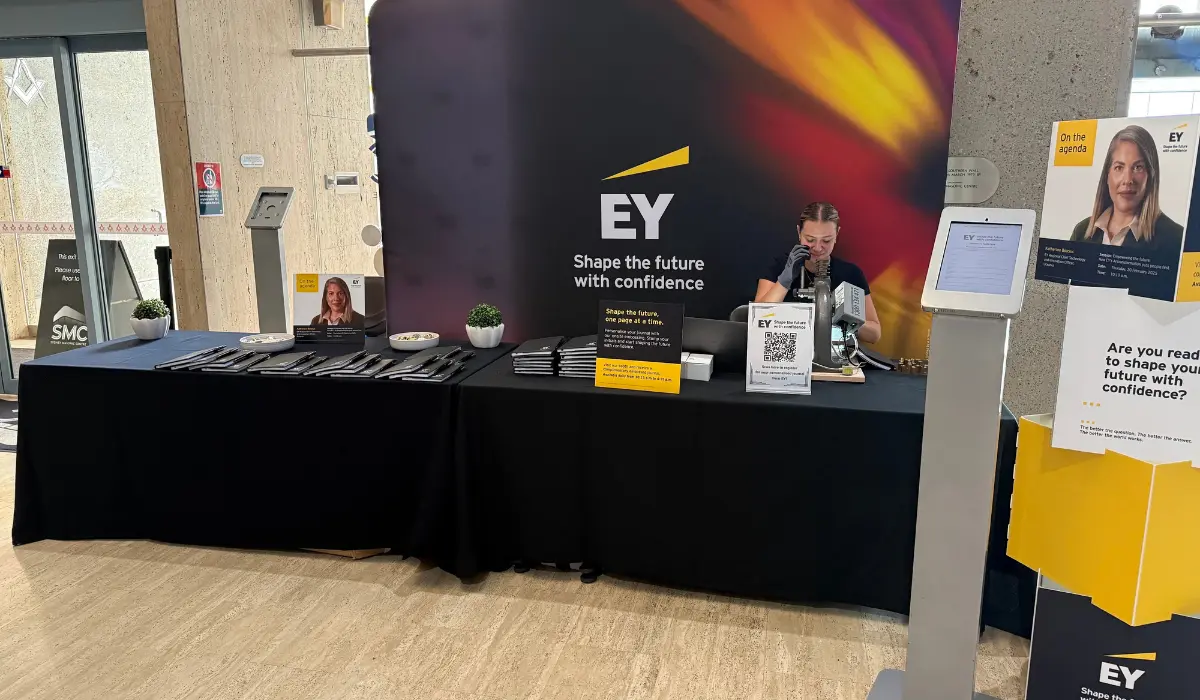 Technician embossing personalised journals at a branded conference activation stand with QR code sign-up
