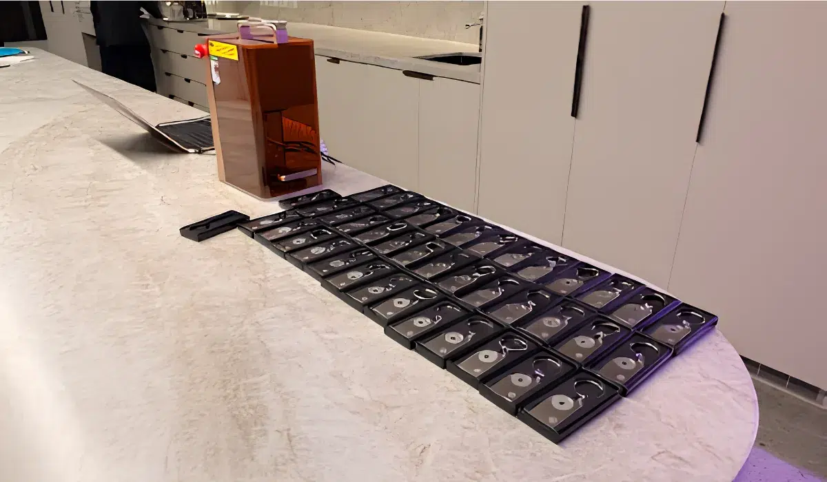 Rows of boxed Charter Hall keyrings beside the live AI engraving machine at the activation