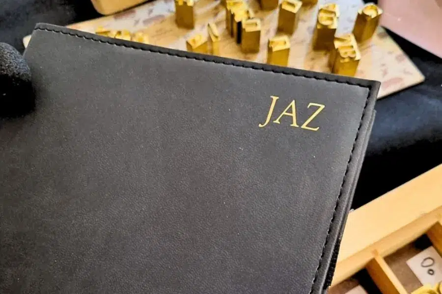 NAB embossed notebook Black notebook embossed with gold initials beside a tray of embossing letter stamps